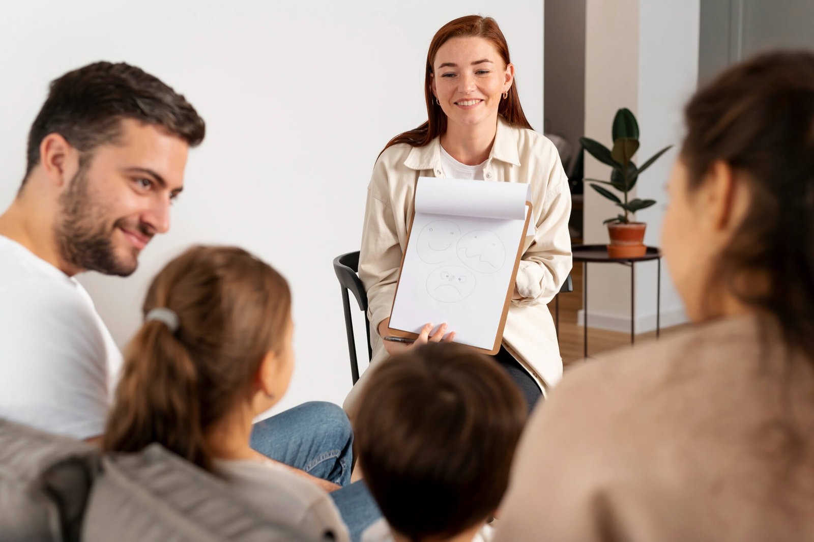 close-up-family-members-talking-therapist Therapist working with smiling family at Therapy Brampton.